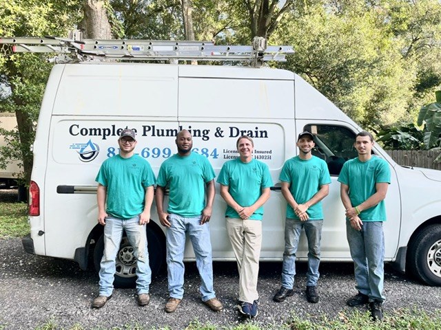 Complete Plumbing and Drain team members standing infront of a logo company van.