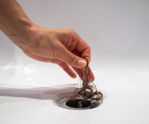 Pulling a hair ball out of a clogged drain for the post Will OxiClean Unclog a Drain that is CLogged?