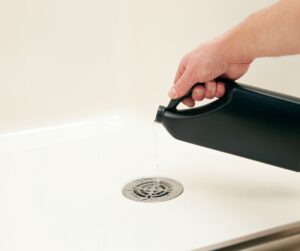 How to fix a gugrling shower drain with a bottle of chemicals being poured.