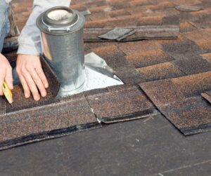 A roofer is working his way around the essential plumbing vent or vertical stack to lay the tiles.